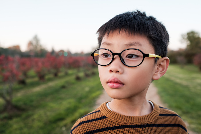 Boy with glasses standing in field